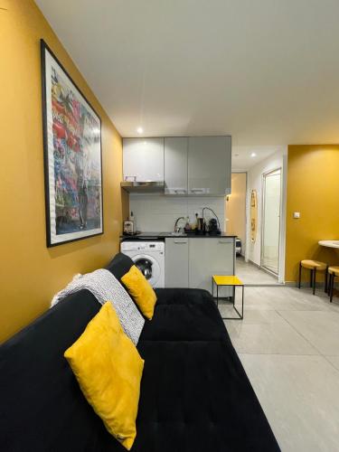 un salon avec un canapé noir avec des coussins jaunes dans l'établissement Chic studio Marais Paris centre, à Paris
