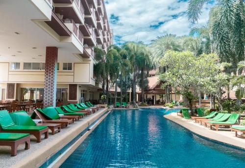 a swimming pool with lounge chairs and a hotel at Baumanburi Hotel Patong in Patong Beach