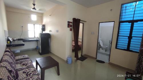 a living room with a couch and a table and a bathroom at Vaidehikunj Homestay in Ayodhya