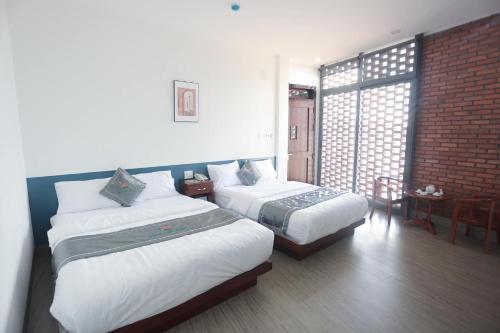 a hotel room with two beds and a window at Khách sạn Sacly in Kon Tum