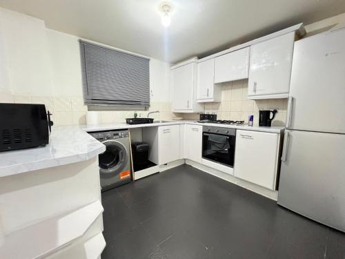 a kitchen with white cabinets and a washer and dryer at High End Luxury 2 Bed Apartment Birmingham in Birmingham
