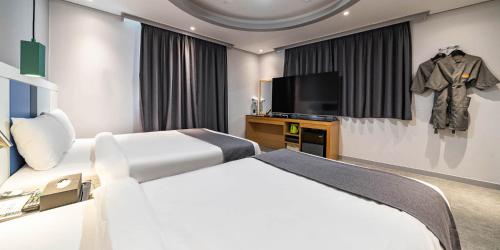 a bedroom with a bed and a flat screen tv at Sokcho Ritz Hotel in Sokcho