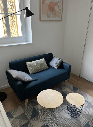 un canapé bleu dans un salon avec deux tables dans l'établissement Maisonnette centre ville, à Laval