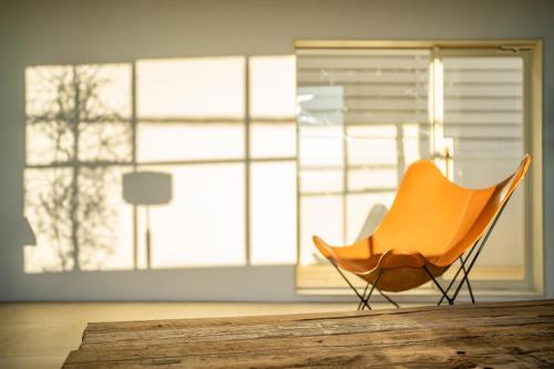 an orange chair in an empty room with windows at Room Tateyama in Hōjō