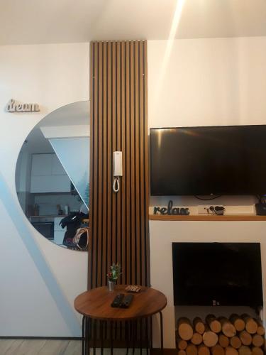 a living room with a fireplace with a television and a table at Borovi30 in Divčibare