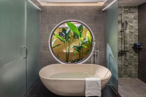 a bathroom with a bath tub with a round mirror at The Signature Hoi An in Hoi An