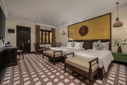 a bedroom with two beds and a table and chairs at The Signature Hoi An in Hoi An