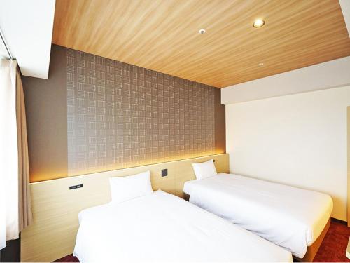 two beds sitting next to each other in a room at CHISUN PREMIUM Kyoto Kujo in Kyoto