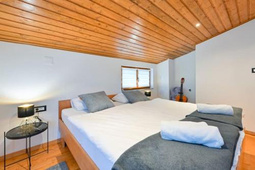 a bedroom with a large white bed and a wooden ceiling at Vila Ivka Holiday Resort in Donja Poljana