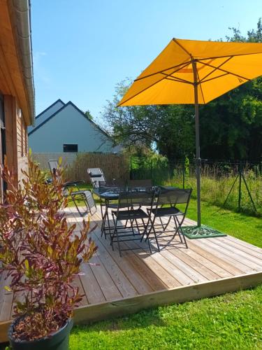 a wooden deck with a table and an umbrella at OUT a TIME in Angoville-sur-Ay