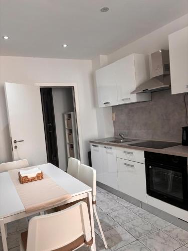 Una cocina con gabinetes blancos y una mesa y sillas. en Le pic de Pierreuse, en Lieja