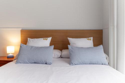 a white bed with two blue and white pillows at Hotel Reina Mora in Granada