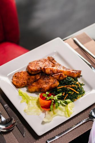 a plate of food with meat and salad on a table at Avian Court Hotel in Naivasha