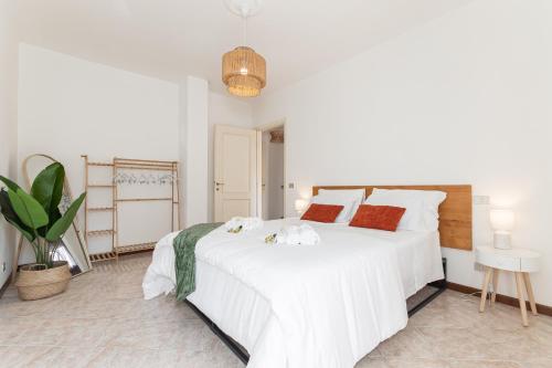 a white bedroom with a large white bed with red pillows at Méditerranée - 200m dal Mare, Parcheggio Privato, Idromassaggio in Imperia