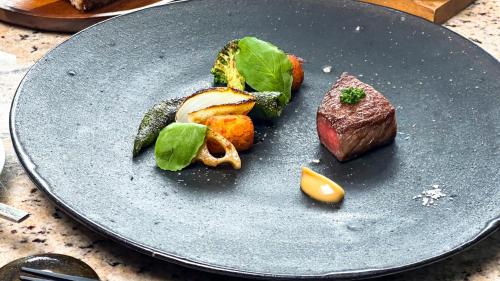 a plate of food with meat and vegetables on a table at ISANA Resort in Ito