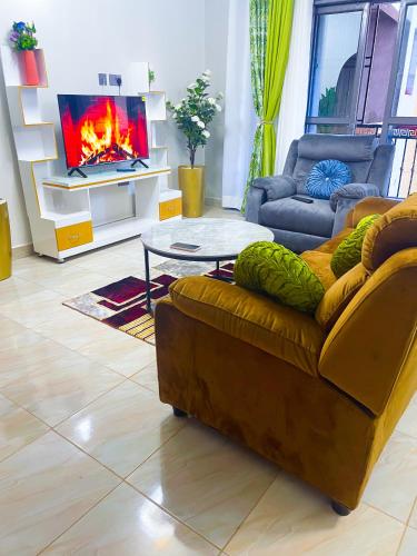 Una sala de estar con un sofá y una chimenea. en Cozy Residence IV 2bedroom Apartment near Speke Resort, en Munyonyo
