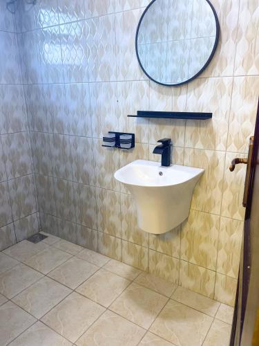 Un baño con un lavabo y un espejo en la pared. en Cozy Residence IV 2bedroom Apartment near Speke Resort, en Munyonyo