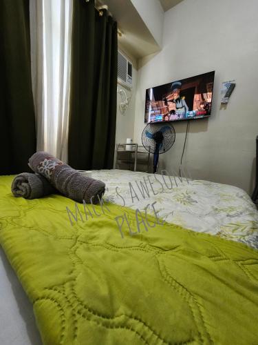 a bed with a green blanket and a tv on the wall at Macks Awesome 12 Place Fast Wifi Netflix in Manila