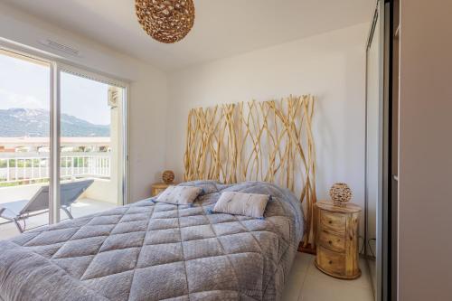 une chambre avec un grand lit et un balcon dans l'établissement Inka - appt vue mer et montagne, à Lumio