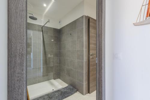 une salle de bain avec une douche avec une porte vitrée dans l'établissement Inka - appt vue mer et montagne, à Lumio