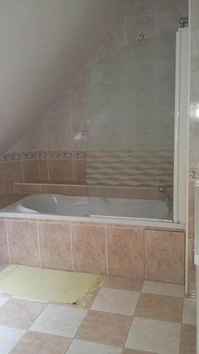 La salle de bains est pourvue d'une baignoire et de carrelage. dans l'établissement Maison spacieuse à Courtils, à Courtils