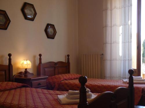 a bedroom with two beds and a lamp and a window at Agriturismo Le Case di San Vivaldo in Montaione