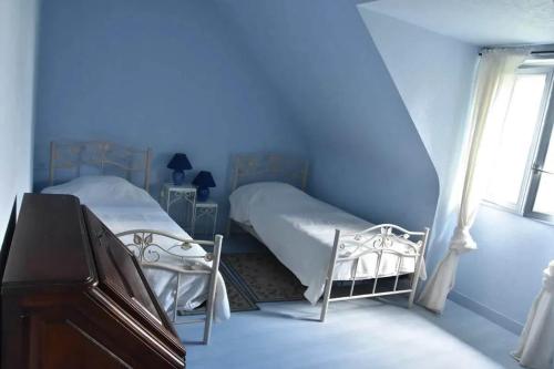 1 dormitorio azul con 2 camas y ventana en Maison de charme avec jardin à Courtils, proche du Mont Saint-Michel, en Courtils