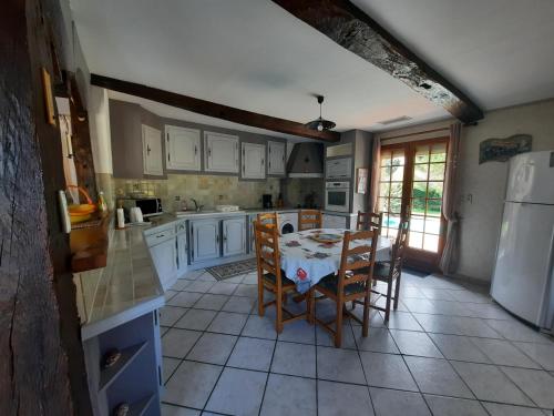 une cuisine avec une table, des chaises et un réfrigérateur dans l'établissement Gîte de Maurin campagne, à Marguestau