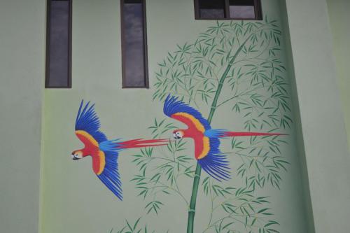 a painting of two parrots on a wall at Mavi Surf Hotel Dominical in Dominical
