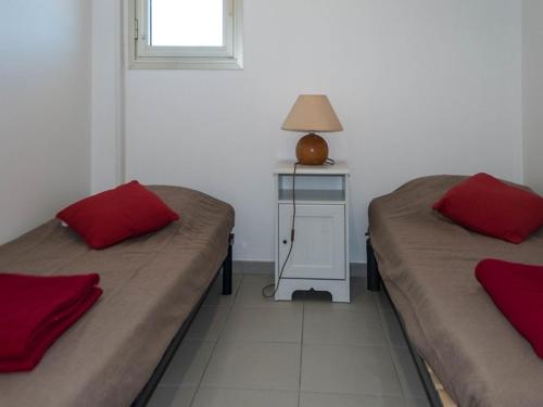 une chambre avec deux lits et une table avec une lampe dans l'établissement T2 au Lavandou, 4 pers, accès plage, Wi-Fi, clim, parking - FR-1-803-62, au Lavandou