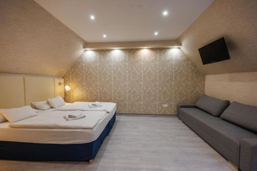 a small room with a bed and a couch at Bástya Konferencia és Wellness Hotel in Miskolctapolca