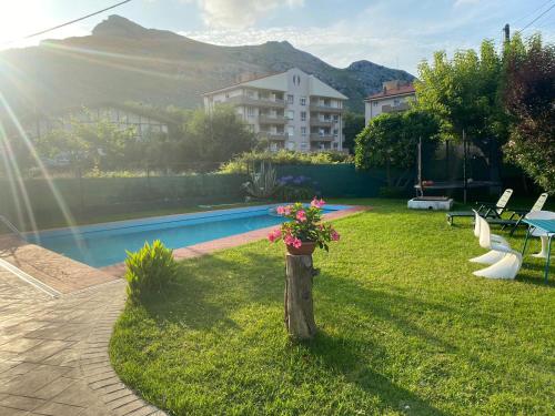 a yard with a pool and a flower pot on a pole at Casa la Choza, con piscina en la playa de Oriñón in Oriñón