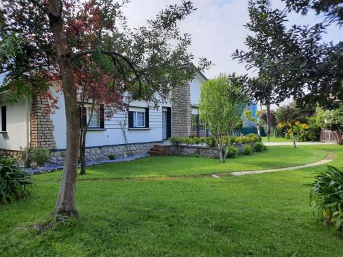 a house with a yard with a tree at Casa la Choza, con piscina en la playa de Oriñón in Oriñón