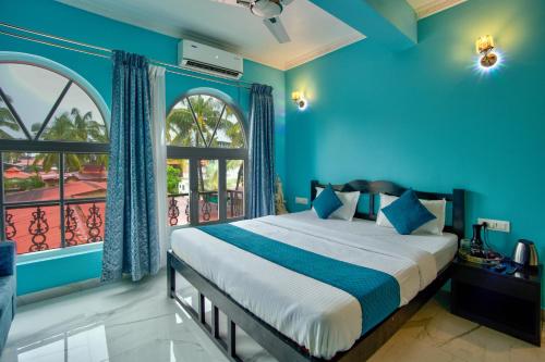 a blue bedroom with a bed and a window at Candolim Beach White Residency in Baga