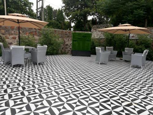 a patio with chairs and tables and umbrellas at Qubes Farmhouse Near Manesar in Manesar