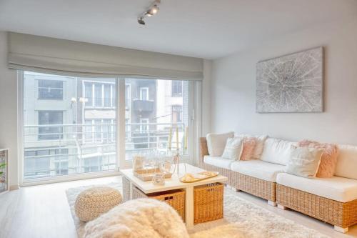 Una sala de estar con un sofá y una ventana grande. en Seaside Serenity Cozy 2-BR Escape, en Blankenberge