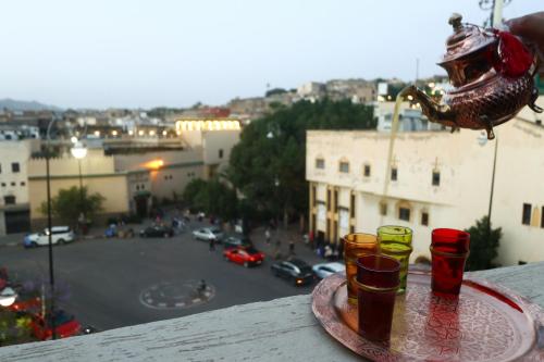 a tray with four cups on a ledge with a view of a street at Dar Ibn Majdoub Lala aicha & Alia in Fès