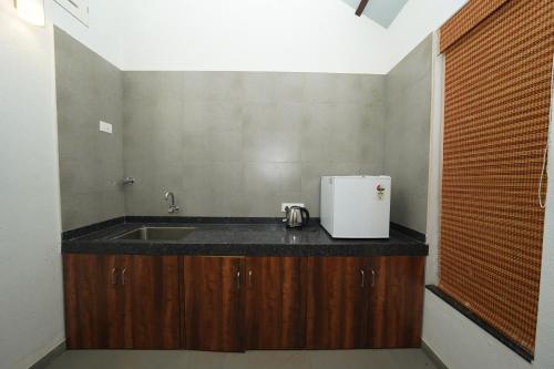 a kitchen with a sink and a refrigerator on a counter at Bougain Villa Resort Park By Dream Villas in Pune