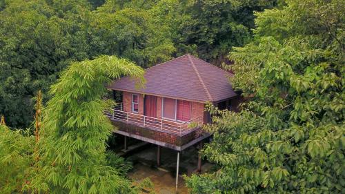 a small red house in the middle of trees at Bougain Villa Resort Park By Dream Villas in Pune