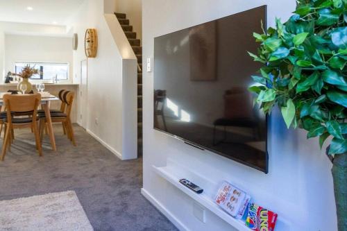 a living room with a large flat screen tv on a wall at 3 Minutes walk to Riverside Market 4bed4bath in Christchurch