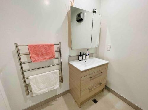 a bathroom with a sink and a mirror and towels at 3 Minutes walk to Riverside Market 4bed4bath in Christchurch