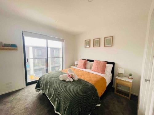 a bedroom with a bed with a stuffed animal on top of it at 3 Minutes walk to Riverside Market 4bed4bath in Christchurch