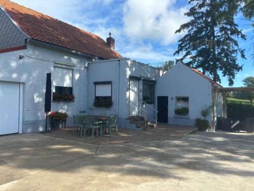 a white house with a table and chairs outside at Le Gîte du Mont de la Hutte in Ploegsteert