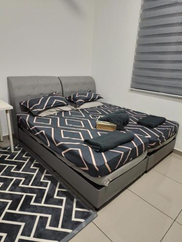 a bed in a bedroom with a black and white comforter at 4D Homestay TSNU Tampin with pool n Bbq set in Tampin