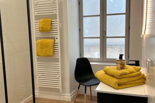 La salle de bains est pourvue d'un bureau, d'une chaise et de serviettes jaunes. dans l'établissement Casa Clemenceau #1, #2, #3 et #4 - T2 très haut standing - Climatisation - Centre Ville, à Brive-la-Gaillarde
