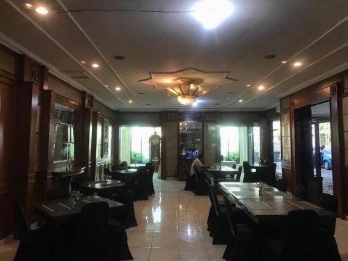 a restaurant with tables and chairs and a chandelier at Larisae Setia Kawan Hotel in Solo
