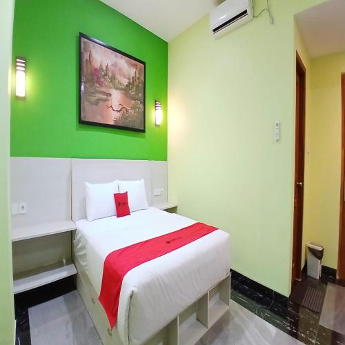a bedroom with a white bed with a green wall at RedDoorz at Griya Athaya Maguwoharjo Yogyakarta in Seturan