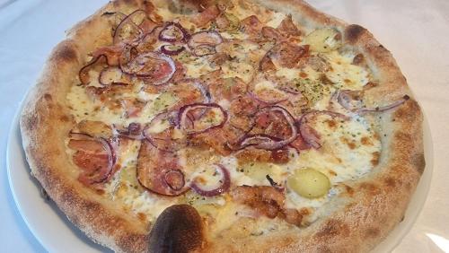 a pizza sitting on a plate on a table at Hôtel Saint Jacques in Thorigné-sur-Dué