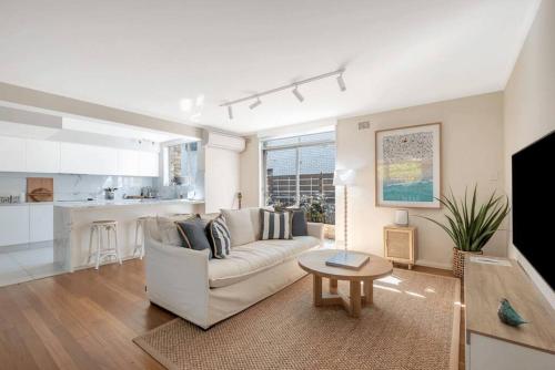 a living room with a couch and a table and a kitchen at Luxe-Coastal Balmoral Townhouse in Sydney