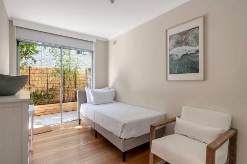 a bedroom with a bed and a chair and a window at Luxe-Coastal Balmoral Townhouse in Sydney